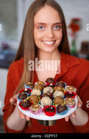 Femme souriante tenant une assiette de bouchées d'énergie saines Banque D'Images