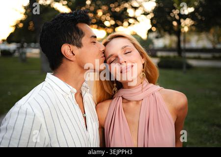 Couple partage un moment tendre dans un parc serein au coucher du soleil Banque D'Images