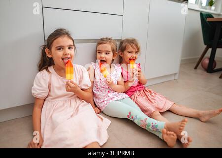 Trois filles apprécient les éclats de glace vibrants tout en étant assis à l'intérieur Banque D'Images