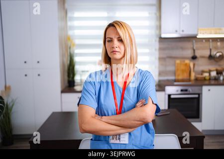 Médecin ou infirmière femme sérieuse avec les bras croisés dans une cuisine Banque D'Images