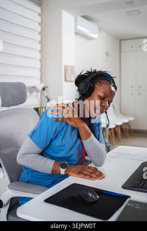Femme professionnelle médicale éprouvant des douleurs à l'épaule dans le bureau Banque D'Images