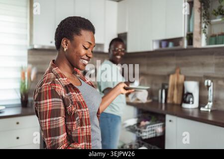 Jeune couple faisant la vaisselle dans la cuisine moderne Banque D'Images