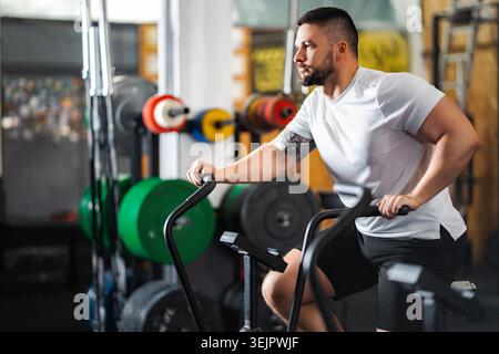 Homme exerçant sur le vélo d'air faisant l'entraînement cardio Banque D'Images