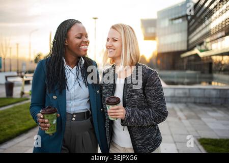 Femmes d'affaires diverses profitant d'une pause café, souriant et ayant une conversation Banque D'Images