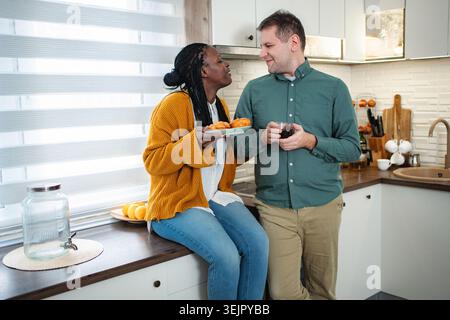 Couple diversifié appréciant le petit déjeuner ensemble dans une cuisine moderne Banque D'Images