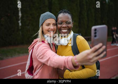 Diverses femmes amies prenant selfie sur la piste de course Banque D'Images