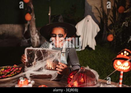 Fille portant un costume de sorcière tenant la lanterne d'Halloween effrayante pendant un bal masqué Banque D'Images