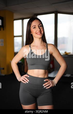 Jeune femme souriante dans le gymnase sportswear se sentant en forme et en bonne santé Banque D'Images