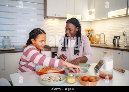 Mère fille préparant la pizza maison ensemble dans la cuisine Banque D'Images