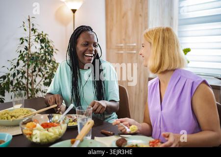 Les amis partagent un repas joyeux ensemble dans une salle à manger confortable Banque D'Images