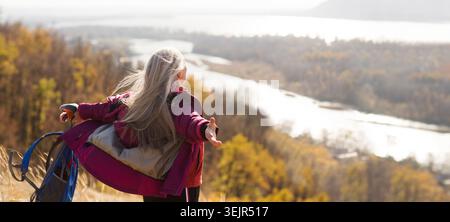 Femme senior avec les cheveux gris se tient sur la montagne et regarde dans la distance et marche en automne en plein air. copier l'espace. mentale Banque D'Images