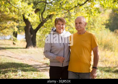 Heureux couple senior regarder la caméra posant et embrassant les uns les autres par une chaude journée d'automne. copier l'espace. Banque D'Images