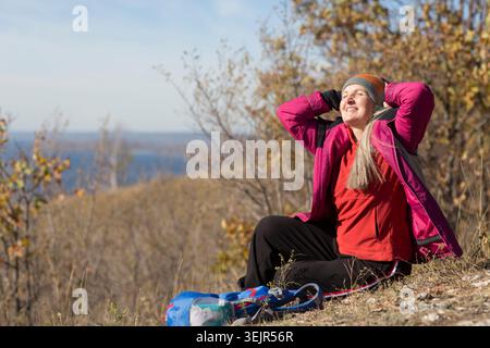 Femme senior avec les cheveux gris est assis sur la montagne et regarde dans la distance et marche en automne en plein air. copier l'espace. mental h Banque D'Images