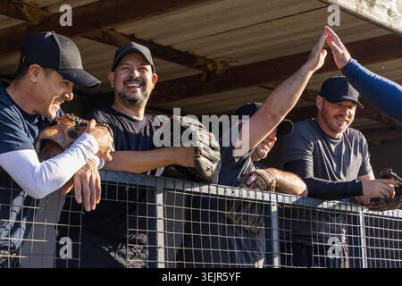 Joueurs de baseball matures sur la rampe de dugout tenant des gants haut-fiving bras entrant, célébrant l'équipe. Athlètes, mitaines, casquettes, outdo Banque D'Images