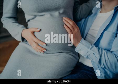Femme enceinte et partenaire touchant la bosse de bébé à la maison de près Banque D'Images