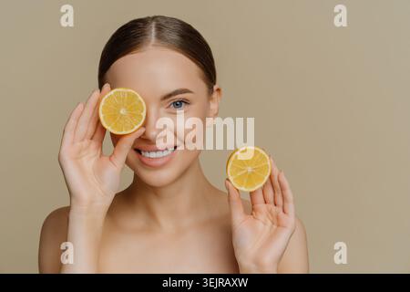 Femme souriante tenant des tranches de citron dans le portrait naturel de beauté de soin de la peau Banque D'Images