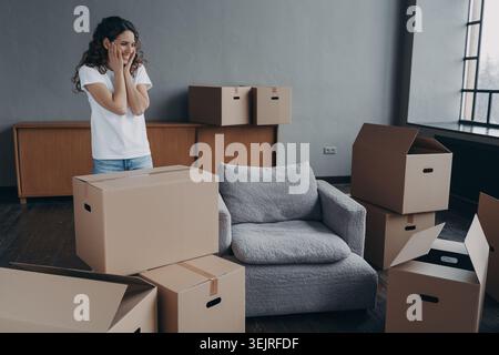 Jeune femme sourit en déballant des boîtes en carton dans le nouveau salon de l'appartement Banque D'Images