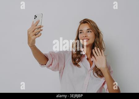 Jeune femme prenant selfie smartphone et agitant tout en créant du contenu de médias sociaux à l'intérieur Banque D'Images