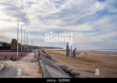Une perspective latérale montre la promenade avec des mâts de drapeau, la sculpture les Braves sur le sable et le mémorial en pierre. Le site historique en Normandie str Banque D'Images
