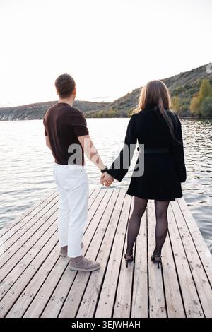 Couple se tient la main, debout sur un quai en bois Banque D'Images