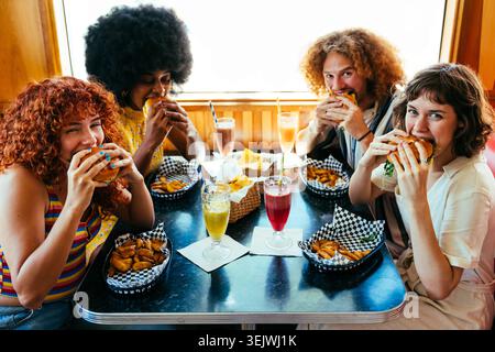 Groupe multiethnique de jeunes amis heureux se liant au restaurant vintage diner burger House - jeunes amis multiethniques appréciant les hamburgers et conversatio Banque D'Images