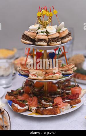 Stand à plusieurs étages rempli de divers hors-d'œuvre pour la célébration de la fête. Les hors-d'œuvre délicieux comprennent des mini hamburgers, des sandwichs et des bruschettas. Variété de g Banque D'Images