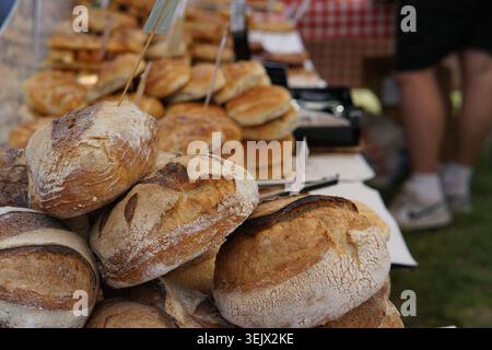 Pains artisanaux frais et petits pains empilés haut à l'étal ensoleillé du marché agricole en plein air, exposition tentante de boulangerie sur Grass.Tonbridge Banque D'Images