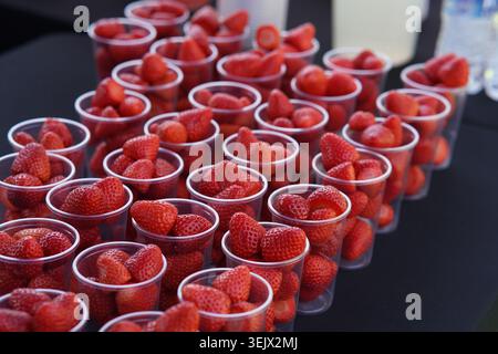Rangées de fraises fraîches mûres dans des gobelets en plastique prêts à être vendus au festival d'été extérieur ensoleillé ou les agriculteurs marchent Stall.Tonbridge Banque D'Images