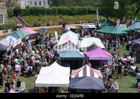 Vue aérienne du festival d'été occupé avec des tentes de marché colorées et une grande foule sur un champ herbeux ensoleillé à l'événement en plein air britannique animé. Banque D'Images