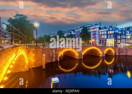 Ponts du canal d'Amsterdam illuminés au coucher du soleil, vue panoramique à l'heure bleue du Reguliersgracht et des maisons hollandaises traditionnelles sans personnes, pays-Bas Banque D'Images