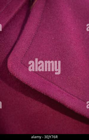 L'image montre une texture macro en gros plan d'une poche ou d'un revers de manteau en laine violette ou magenta éclatante avec des coutures soignées. Banque D'Images