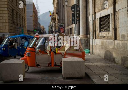 Les taxis Piaggio APE à trois roues colorés sont garés le long d'une rue étroite et historique en Italie. Ces véhicules agissent comme des transports touristiques locaux, en attente Banque D'Images