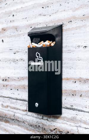 Unité murale extérieure d'élimination de cigarettes remplie de mégots de cigarettes contre un mur de pierre légère à Amsterdam, pays-Bas Banque D'Images