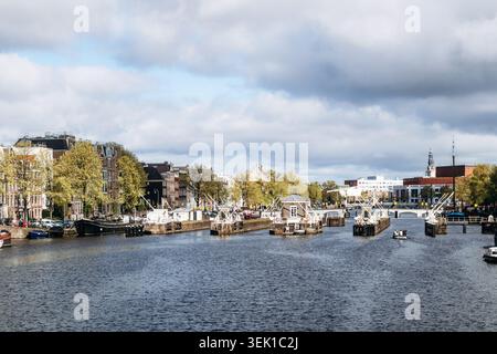 Amsterdam, pays-Bas - 19 avril 2026 : vue panoramique sur la rivière Amstel dans le centre d'Amsterdam avec des ponts-levis historiques, des maisons de canal et le printemps tr Banque D'Images
