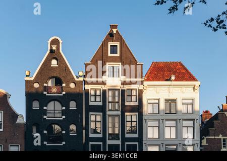 Amsterdam, pays-Bas - 18 avril 2026 : maisons traditionnelles sur le canal d'Amsterdam avec toits à pignons hollandais distinctifs et façades historiques en briques brillantes Banque D'Images