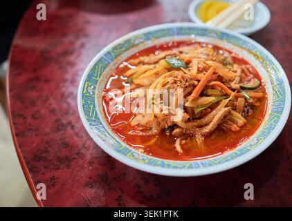 Copieux Jjamppong coréen avec porc râpé et légumes frais dans un bouillon rouge ardent, représenté aux côtés d'une savoureux variation de fruits de mer avec du crabe. Banque D'Images