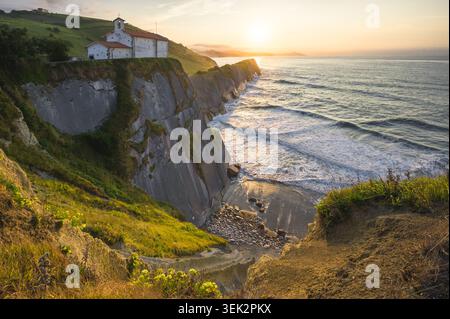 Ancienne chapelle sur les spectaculaires falaises Flysch au coucher du soleil doré sur l'océan Atlantique, Zumaia, pays Basque, Espagne Banque D'Images