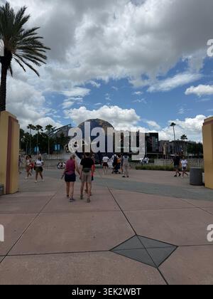 ORLANDO, Floride - 1er JUIN 2026 : une foule de touristes des parcs à thème marche le long de la voie principale vers le globe emblématique des Universal Studios en rotation. Banque D'Images
