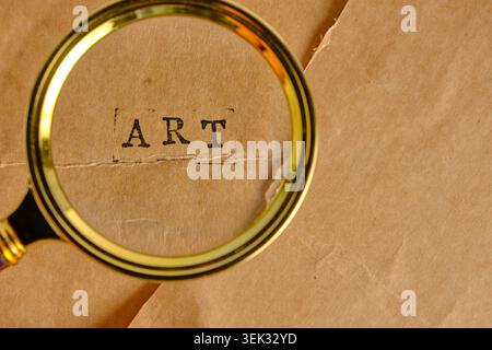 Gros plan loupe dorée mettant en évidence l'ART DE mot estampillé sur une feuille de papier brun Banque D'Images
