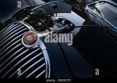 Gros plan du capot d'une voiture Jaguar classique noire montrant la mascotte d'un chat qui saute en chrome et l'écusson en émail rouge Banque D'Images