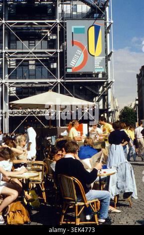 Menschen sitzen an einem sonnigen Tag in einem Straßencafé vor dem Centre Pompidou. An der Fassade des markanten Gebäudes hängt ein Großes Plakat mit der Aufschrift 50 annees 50. Frankreich, 1986 Banque D'Images