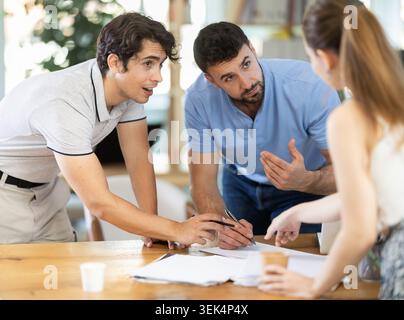 Les collègues travaillent sur le dessin sur papier, font des croquis tout en discutant du plan de construction dans le bureau Banque D'Images
