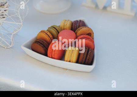 Les macarons colorés dans un bol blanc sont assis de manière tonitruante Banque D'Images