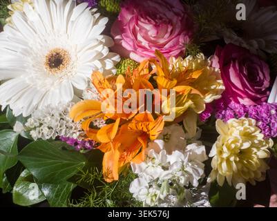 Vue en angle élevé d'un bouquet de fleurs multicolores vibrant avec des lis gerbera et des roses. Banque D'Images