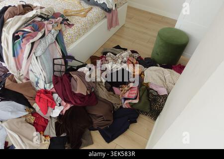 Vêtements éparpillés sur le sol dans la chambre en désordre Banque D'Images
