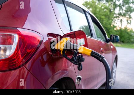 Ravitaillement en carburant d'un véhicule : processus de ravitaillement à une station-service avec un accent sur le bouchon de carburant d'une voiture et le pompage du carburant dans le réservoir d'essence Banque D'Images