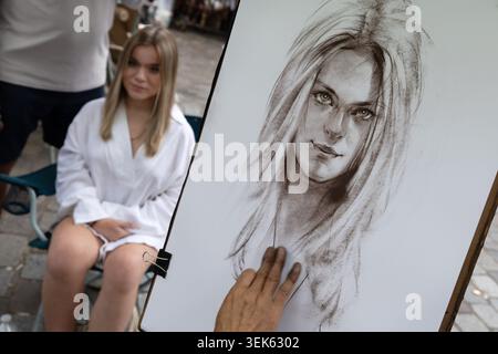 L'artiste de rue de Montmartre dessine le portrait d'une jeune femme assise à Paris. Banque D'Images