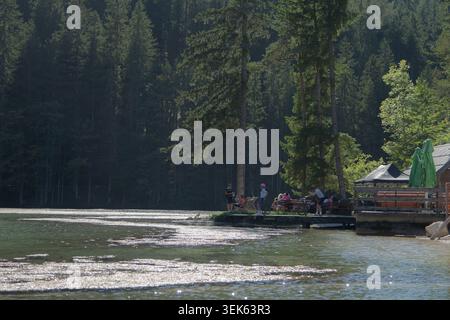 Les gens se détendent sur un quai au bord du lac à côté d'une forêt calme et de l'eau pétillante par une journée ensoleillée Banque D'Images