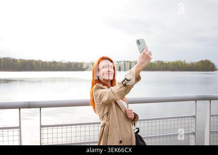 Femme d'âge moyen voyageur solo avec les cheveux rouges faisant selfie avec un Banque D'Images