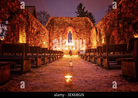 Pälkäne, Finlande - 25 décembre 2020 : scène de Noël festive dans des ruines historiques avec des bougies allumées, un sol enneigé et des sièges en bois rustiques Banque D'Images